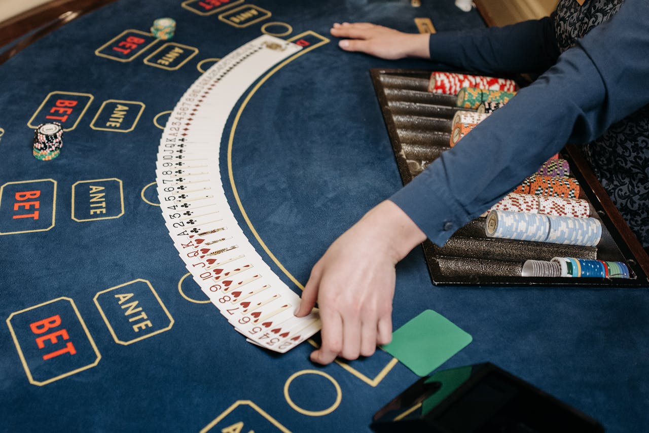 A casino dealer organizing playing cards on a gaming table with chips. Indoors setting.